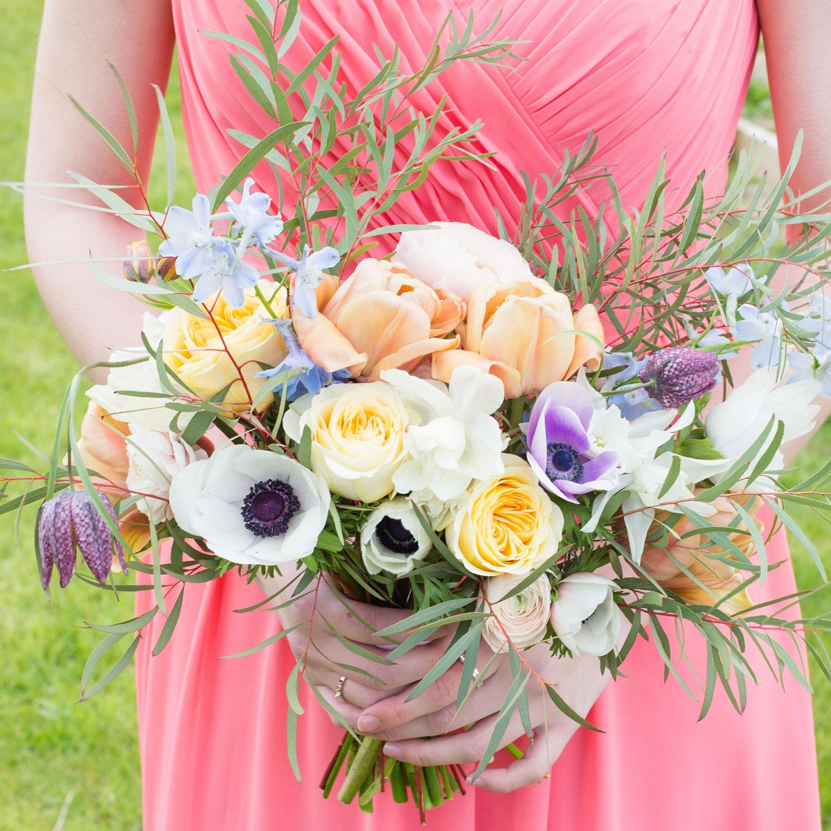 Woman in a pink bridesmaid dress holding a bouquet of spring wedding flowers